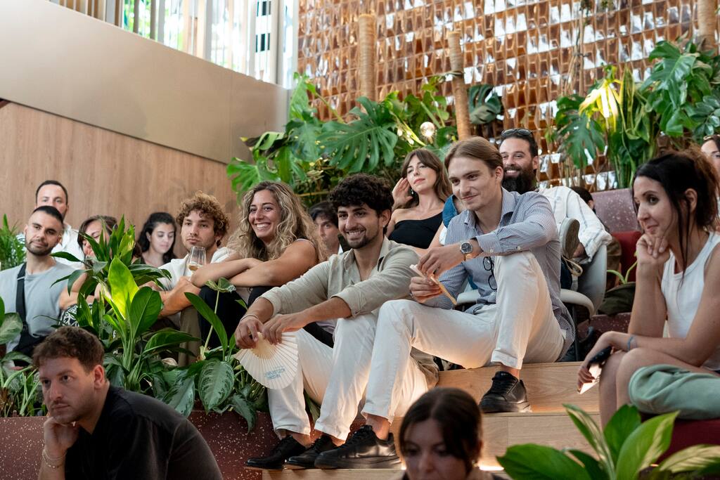 An audience of young adults smiling and watching an event